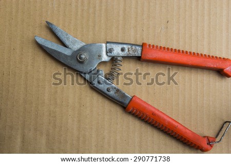 Pliers used to cut sheet metal plate. The handheld is placed on rubber, plastic, red brown background.