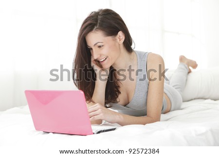 Pretty girl smiling at her computer while typing on the keyboard