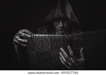 Dark necromancer and grimoir, a warlock casting black magic from his magic book, halloween concept, black and white