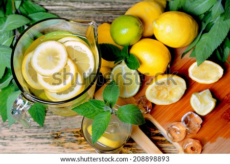 Lemonade in the jug with mint and lemon on the table. Preparation of the lemonade drink.