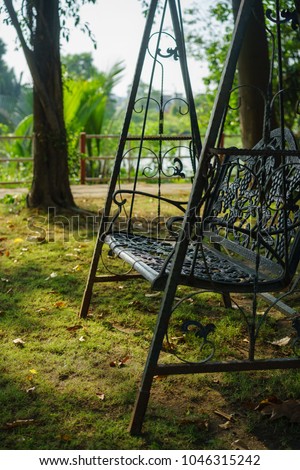 black iron classic outdoor hanging patio porch swing bench in the garden. swing in the park - Bench under the tree.