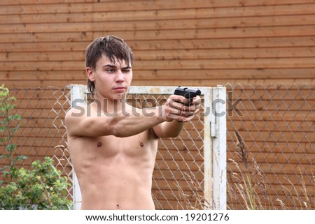 Portrait of a young nude man with gun