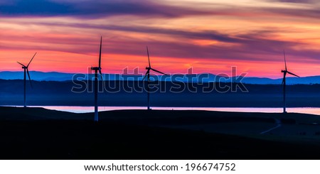 Giant wind turbines standing up the hills near the waterside of Lake George, NSW, Australia