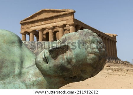 The Temple of Concordia in The Valley of the temples behind the bronze sculpture of Icarus, person of greek mythology.