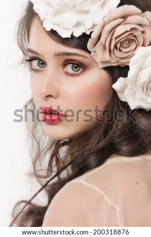 Portrait of the innocent young girl with big beautiful eyes,  gentle make-up and hairstyle isolated on white background. Trendy fashion wedding look. Big  Flowers and bridal hairdo