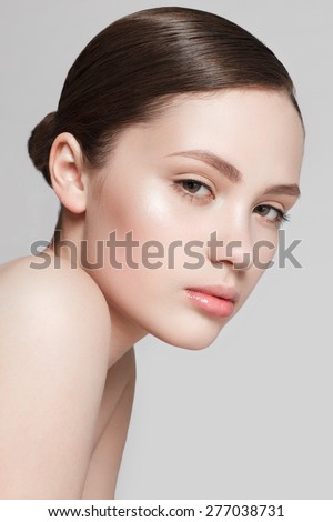 Beautiful face of young woman with clean fresh skin and natural make-up on grey background