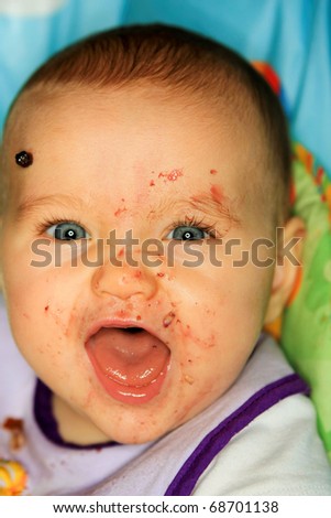 A joyful baby with food splattered all over her face