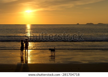 Two Children watching the ocean sunset with their dog