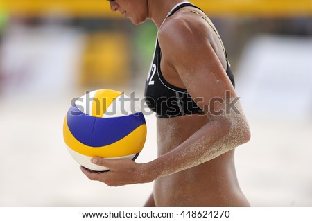 Volleyball player is a female athlete playing beach volley ball getting ready to serve the ball.