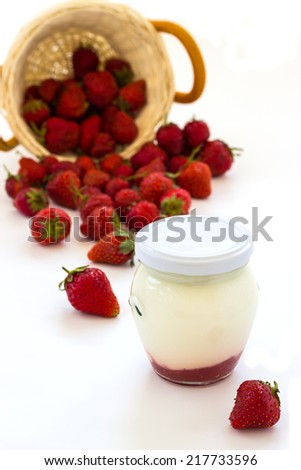 Strawberry yogurt in a glass jar and basket of strawberries on