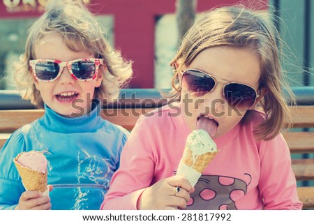 Two little girls (sisters) eating ice cream.