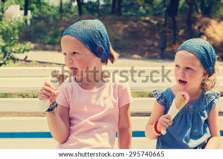 Little cute girls (sisters) eat ice cream, selective focus.