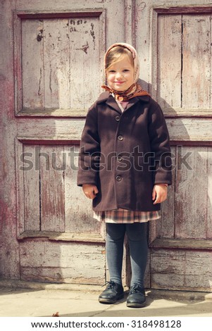 Vintage style. Little cute girl on the background of the old door. Selective focus.