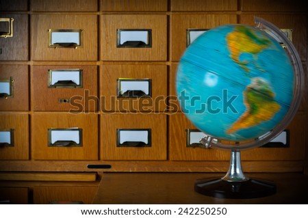 Vintage Spinning Globe in Front of Old Library Card Catalog Stock Photo