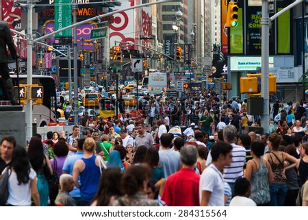 New York, USA - June 30, 2009: A crowd moves through Times Square, next to the Avenue of Broadway full of traffic and under a maze of lights and advertisements.