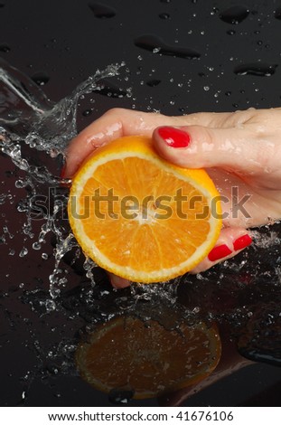 orange is dropped into water splash on black