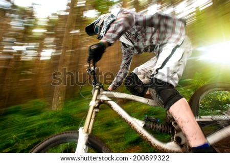 Mountain biker going fast downhill with speed blur and trees in the background