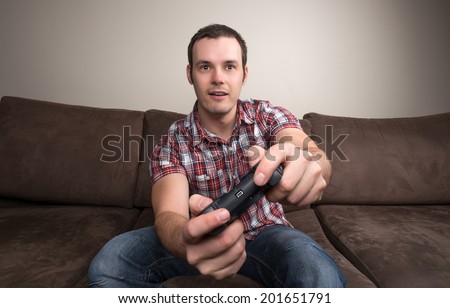 Young man playing video games with a wireless control pad.
