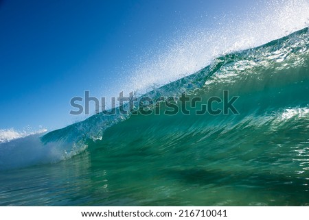 Crystal clear beach break wave with the sun coming through the back of the wave.