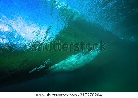 Underwater shot of a wave barreling over with blue sky showing through
