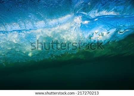 Barreling wave from underwater with blue sky showing through.