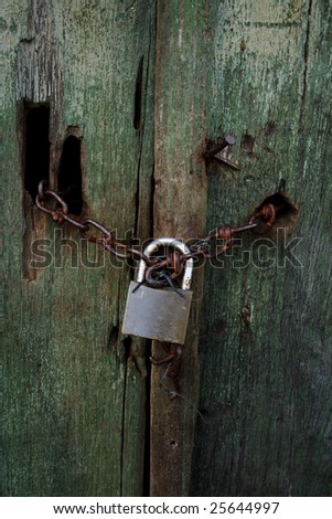 Rusted wood doors of the abandoned house locked with chain and locker.