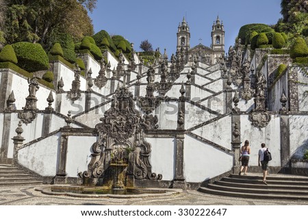 Tourists are approaching stairs with saint\'s statues leading to the church Bom Jesus do Monte near Braga, Portugal