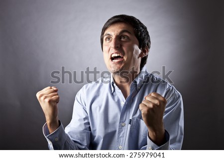 Young Man Shouting and feasting I fill of happiness and emotion on gray background