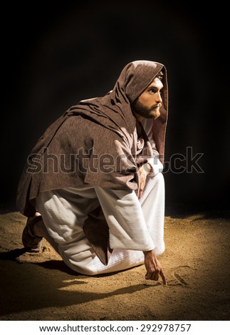 Jesus Christ writing in the sand in the dark black night