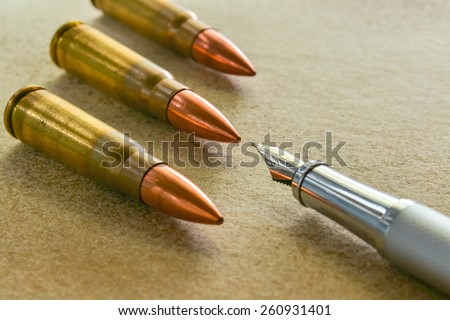 Silver fountain pen and three bullets arranged in the corners of the image
