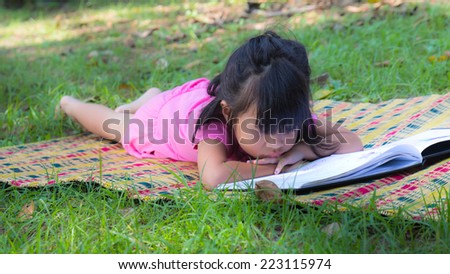 Outdoor portrait of a cute little girl reading a book - Asian people