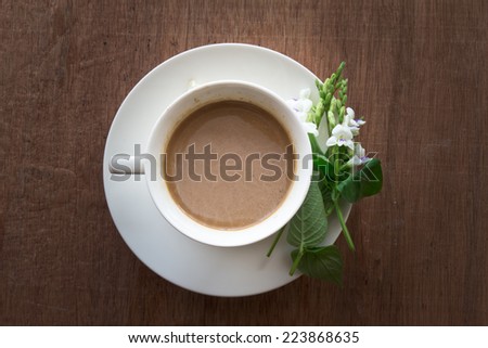 Coffee mug and flower on brown wooden table