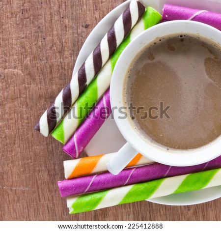 striped wafer rolls filled and coffee on wooden table