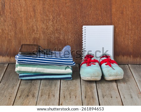 Sneakers, shirt, telephone and earphones on wooden background