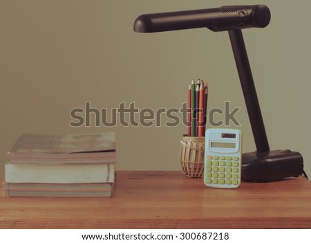 Vintage image, calculator, books and lamp on wooden table, color pencil in bamboo,