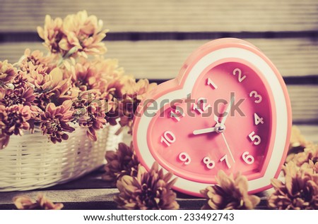 Watch red hearts and flowers in a basket placed on a wooden background. (For a happy time And home decor)