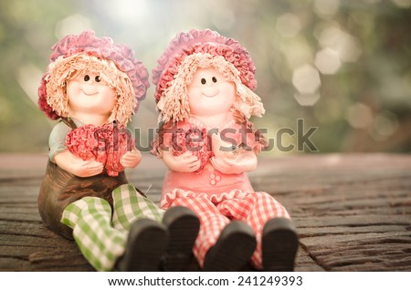 Two Lovely doll sitting on a wooden and bokeh background  in a vintage retro style, with the sunrise, for the day of love, Valentine\'s Day.