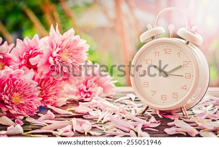 Vintage background.flowers with retro alarm clock on wooden table. black and white