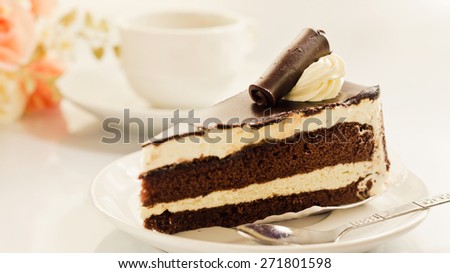 Chocolate with vanilla cream cake and cup of coffee on white background soft focus.