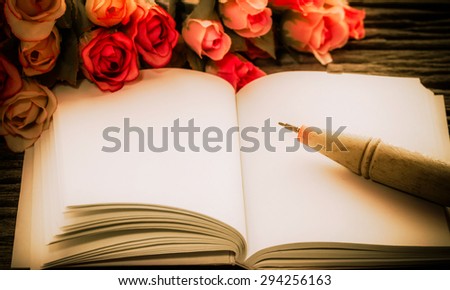 Vintage of note book paper and pen with rose on wooden background soft focus.(dark colors )