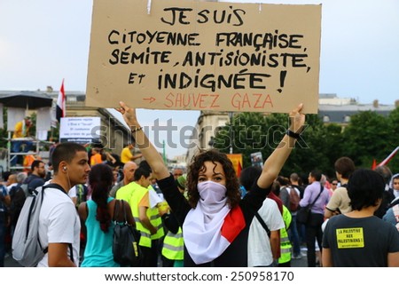 PARIS - JULY 23, 2014: A masked female protester holds up a sign at a pro-Palestine protest in Paris on July 23, 2014. Thousands demonstrated that summer to protest Israel\'s assault on the Gaza Strip.