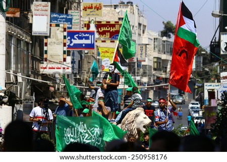 RAMALLAH, PALESTINE - AUGUST 17, 2014: A protester wearing a Guy Fawkes mask stands amidst a crowd at a Hamas rally in Ramallah, Palestine on August 17, 2014.