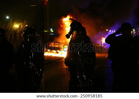 FERGUSON, MO - NOVEMBER 24, 2014: Silhouette of a police officer standing amid flames after riots broke out in Ferguson, Missouri on November 24, 2014.