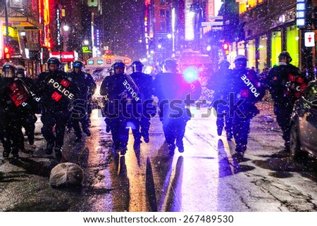 MONTREAL - MARCH 27: Police in heavy riot gear charge at a crowd of protesters during an anti-austerity demonstration on March 27, 2015 in Montreal, Quebec.