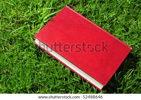 Blank red book on grass.
