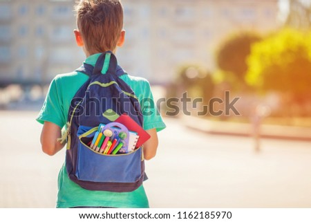Back to school concept. Schoolboy with full backpack go to school. Back view.