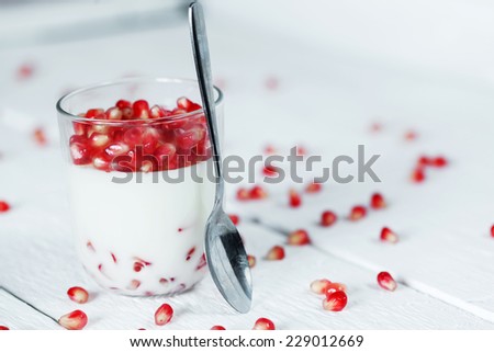 Jelly gelatin cream dessert or panna cotta with pomegranate seeds in glass on white background