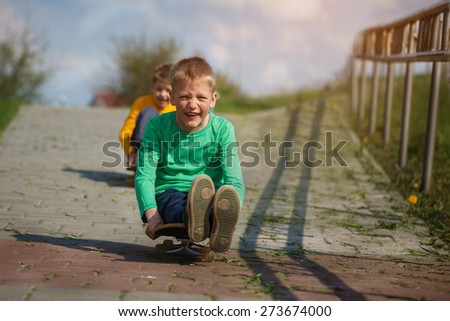 Active childhood. Little man skateboarding. Skater boy child sits on  a skateboard and slides on the road.