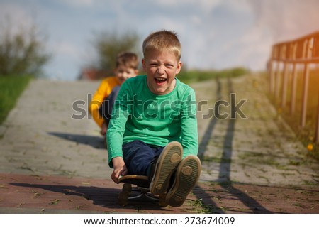Active childhood. Little man skateboarding. Skater boy child sits on  a skateboard and slides on the road.