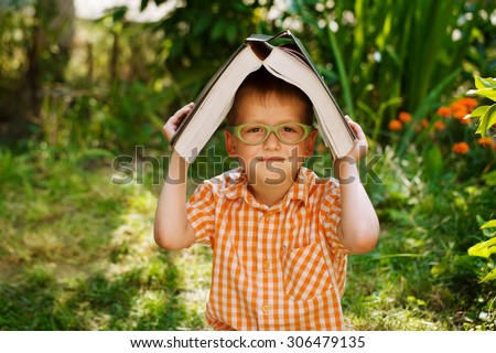 Portrait Happy little boy holding a big book on his first day to school or nursery. Outdoors, Back to school concept